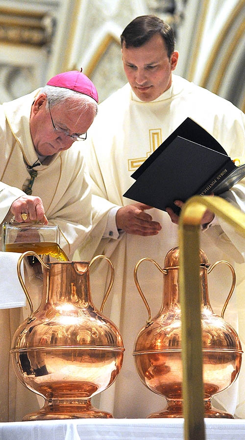 Bishop Richard Malone adds a dark oil to a vessel of olive oil before blessing it at St. Joseph Cathedral during the annual Chrism Mass. (Dan Cappellazzo/Staff Photographer)